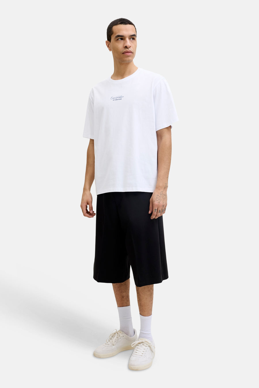 T-shirt blanc de la marque ORIGINALS BY JACK & JONES, avec logo texte discret sur la poitrine, porté avec un short noir et des baskets claires.