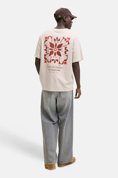 T-shirt beige de la marque ORIGINALS BY JACK & JONES avec motif rouge et texte au dos, porté par un homme.