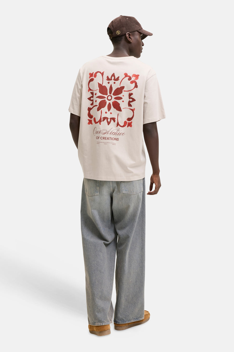 T-shirt beige de la marque ORIGINALS BY JACK & JONES avec motif rouge et texte au dos, porté par un homme.