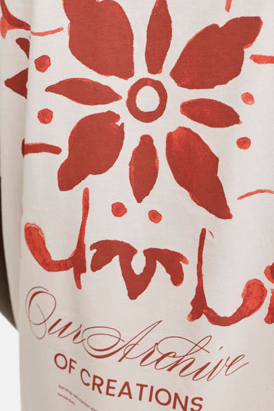 T-shirt beige de la marque ORIGINALS BY JACK & JONES avec un motif floral abstrait rouge brique et l'inscription « Our Archive of Creations ».