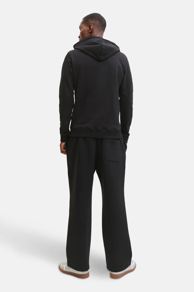 Sweat à capuche noir JACK & JONES, modèle vu de dos porté avec un pantalon large et des chaussures de sport.