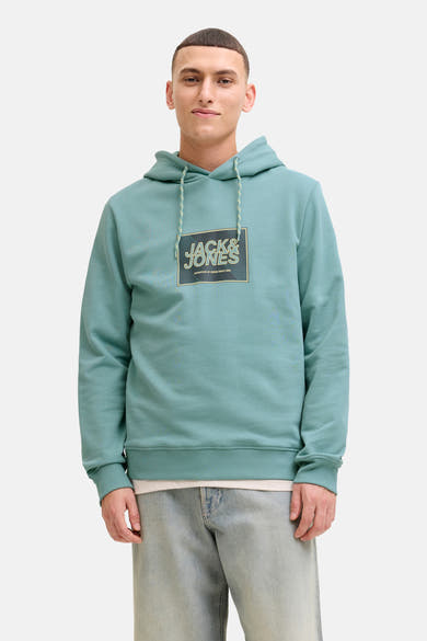 Groene hoodie van JACK & JONES, gedragen met een lichtgewassen spijkerbroek en witte sneakers.