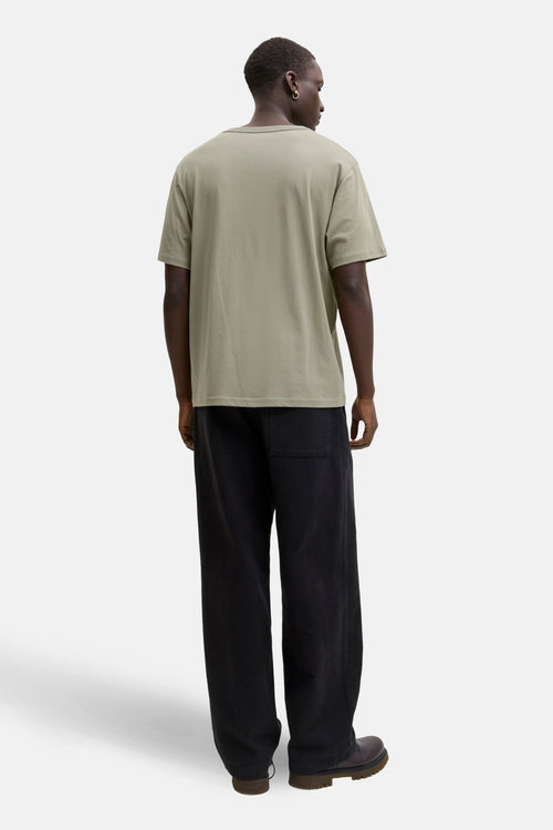 T-shirt à manches courtes vert olive de ORIGINALS BY JACK & JONES, porté avec un pantalon ample noir et des bottes marron, vue de dos.

