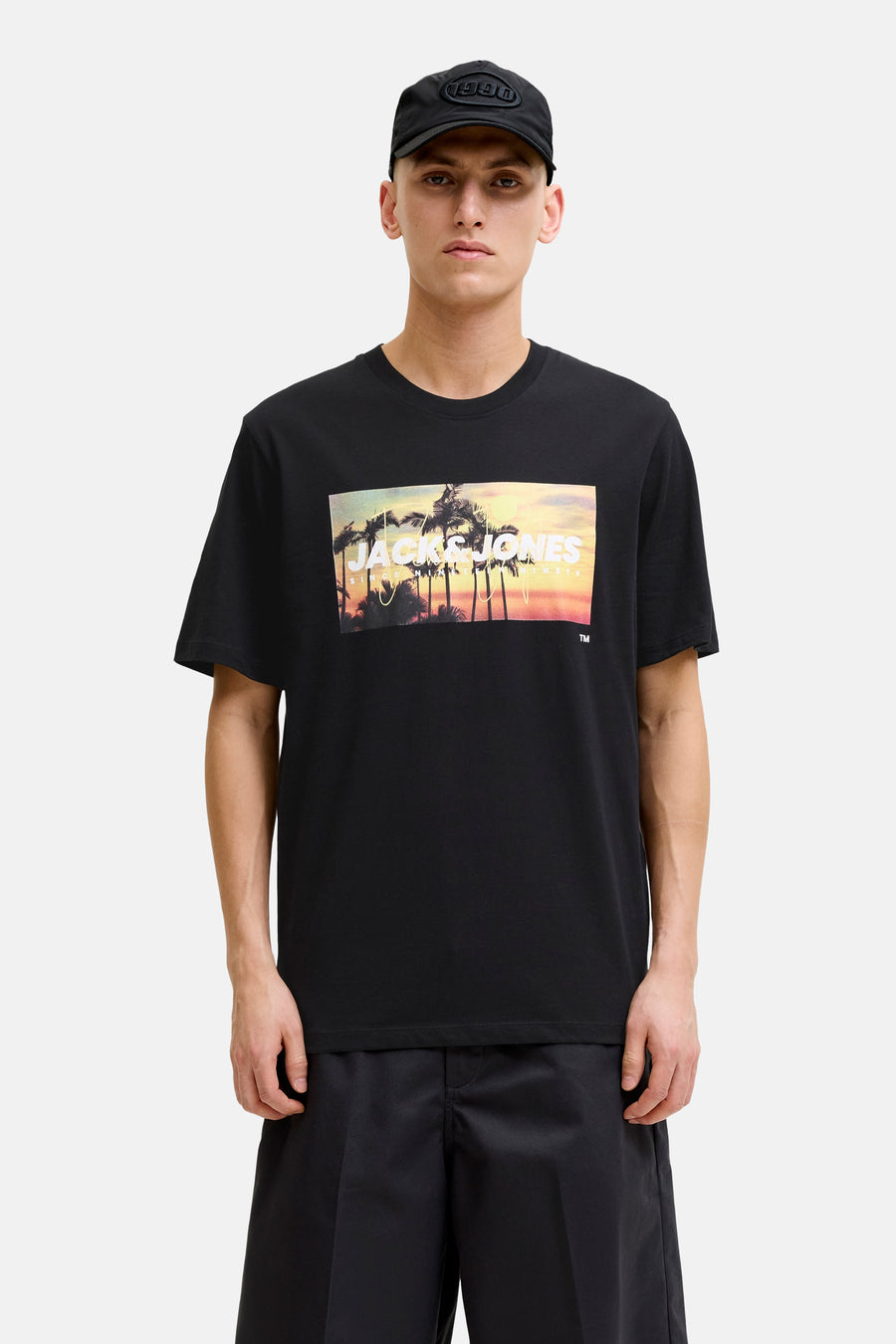 T-shirt noir de JACK & JONES avec un imprimé tropical de palmiers et coucher de soleil sur la poitrine.