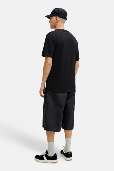 T-shirt noir de JACK & JONES, porté de dos avec un short, une casquette, des chaussettes grises et des baskets.
