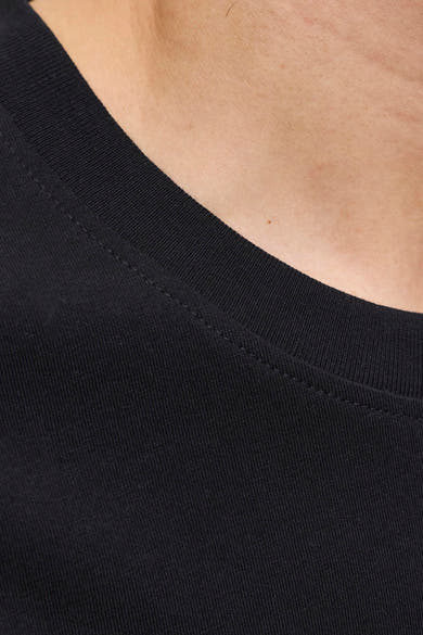 Gros plan sur le t-shirt noir de JACK & JONES avec col côtelé et couture visible sur peau claire.