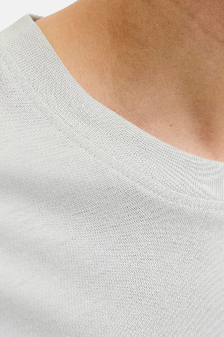 T-shirt blanc de JACK & JONES, plan rapproché sur l'encolure ras-du-cou côtelée et les piqûres apparentes sur la peau.