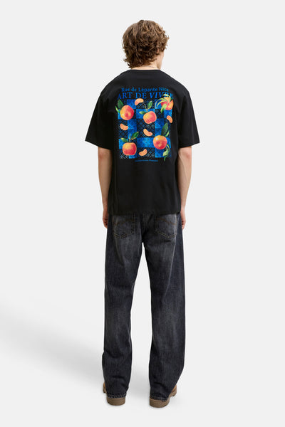Black short-sleeve T-shirt with vibrant peach and blue geometric back print, worn by model in dark jeans, back view