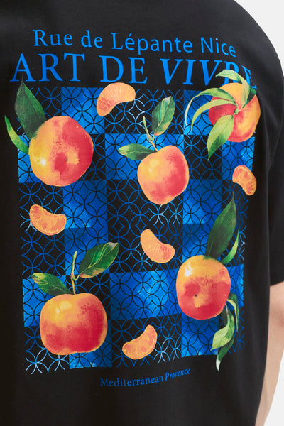 Black short-sleeve t-shirt with vibrant fruit print and blue geometric pattern, featuring "Art de Vivre" text, front view