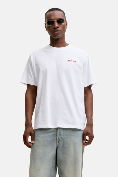 White short-sleeve t-shirt with red chest text, worn by model in lifestyle front view, paired with light blue jeans