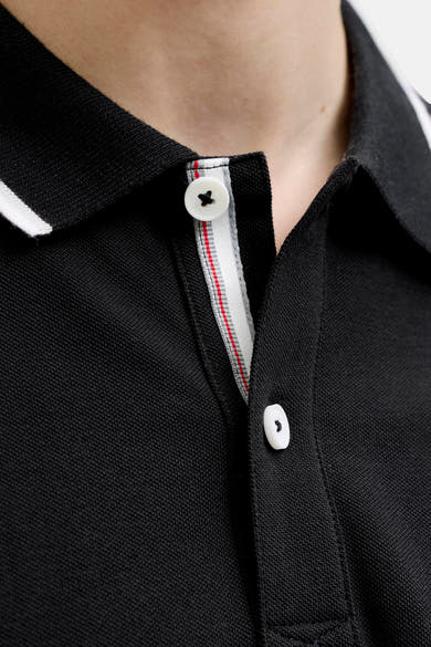 Polo noir de JACK & JONES en maille piquée, col avec liseré blanc et patte de boutonnage avec bande intérieure rayée.