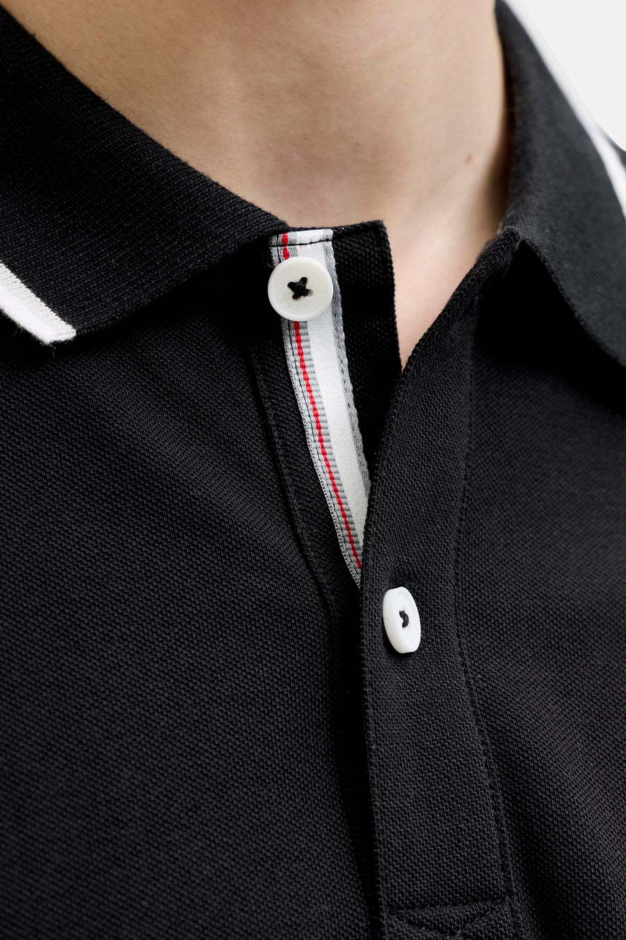 Polo noir de JACK & JONES en maille piquée, col avec liseré blanc et patte de boutonnage avec bande intérieure rayée.