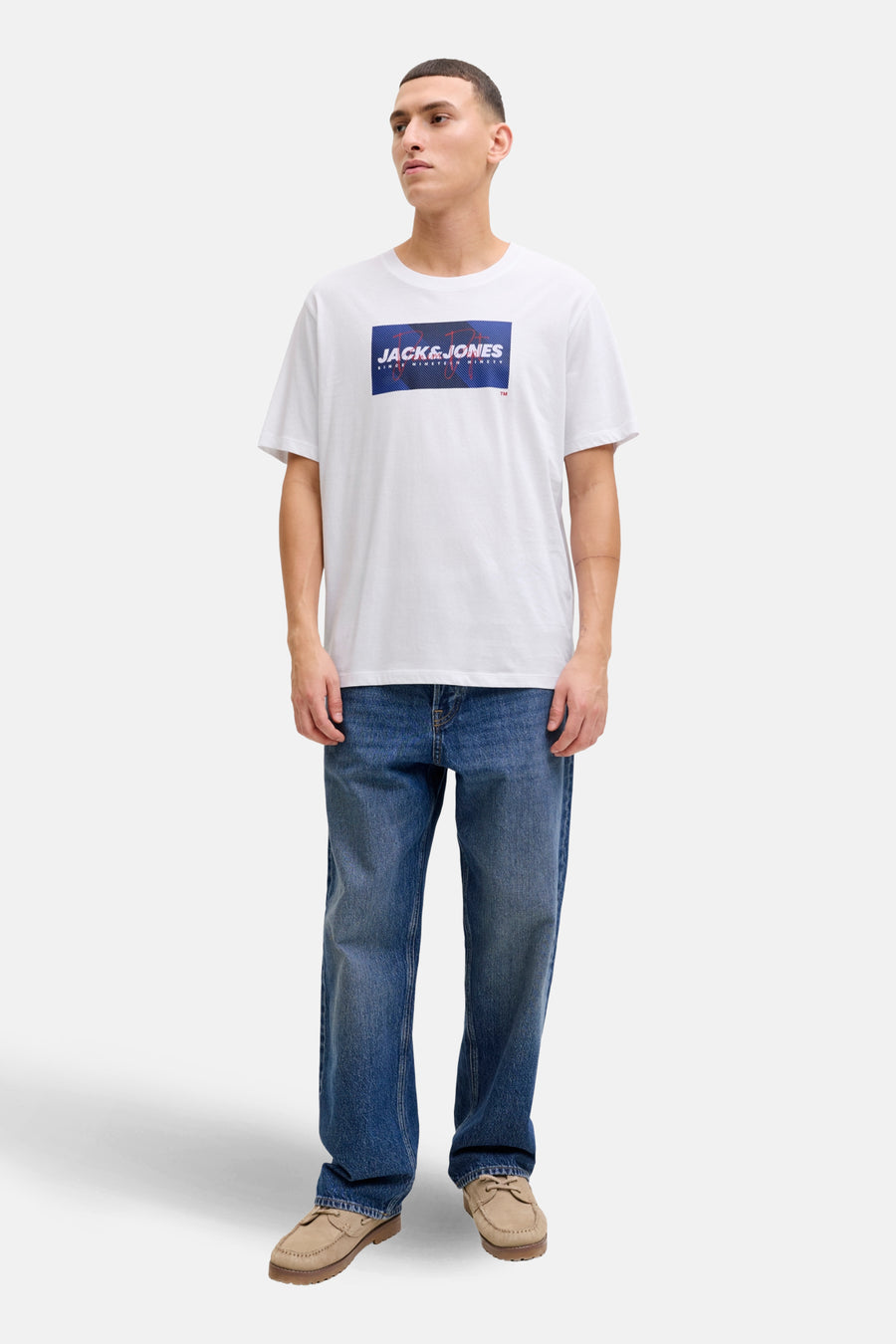 T-shirt à manches courtes blanc de JACK & JONES, porté avec un jean bleu et des chaussures bateau beiges.