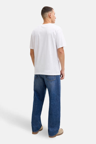 Wit T-shirt met korte mouwen van JACK & JONES, gedragen met een blauwe jeans en zandkleurige schoenen, achtergezicht.