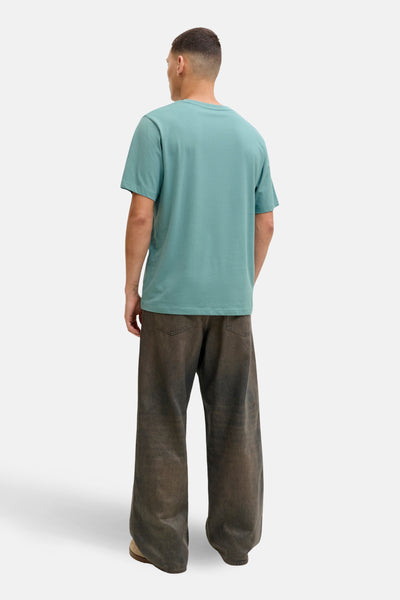 T-shirt bleu à manches courtes de JACK & JONES, vue de dos, porté avec un pantalon large marron.
