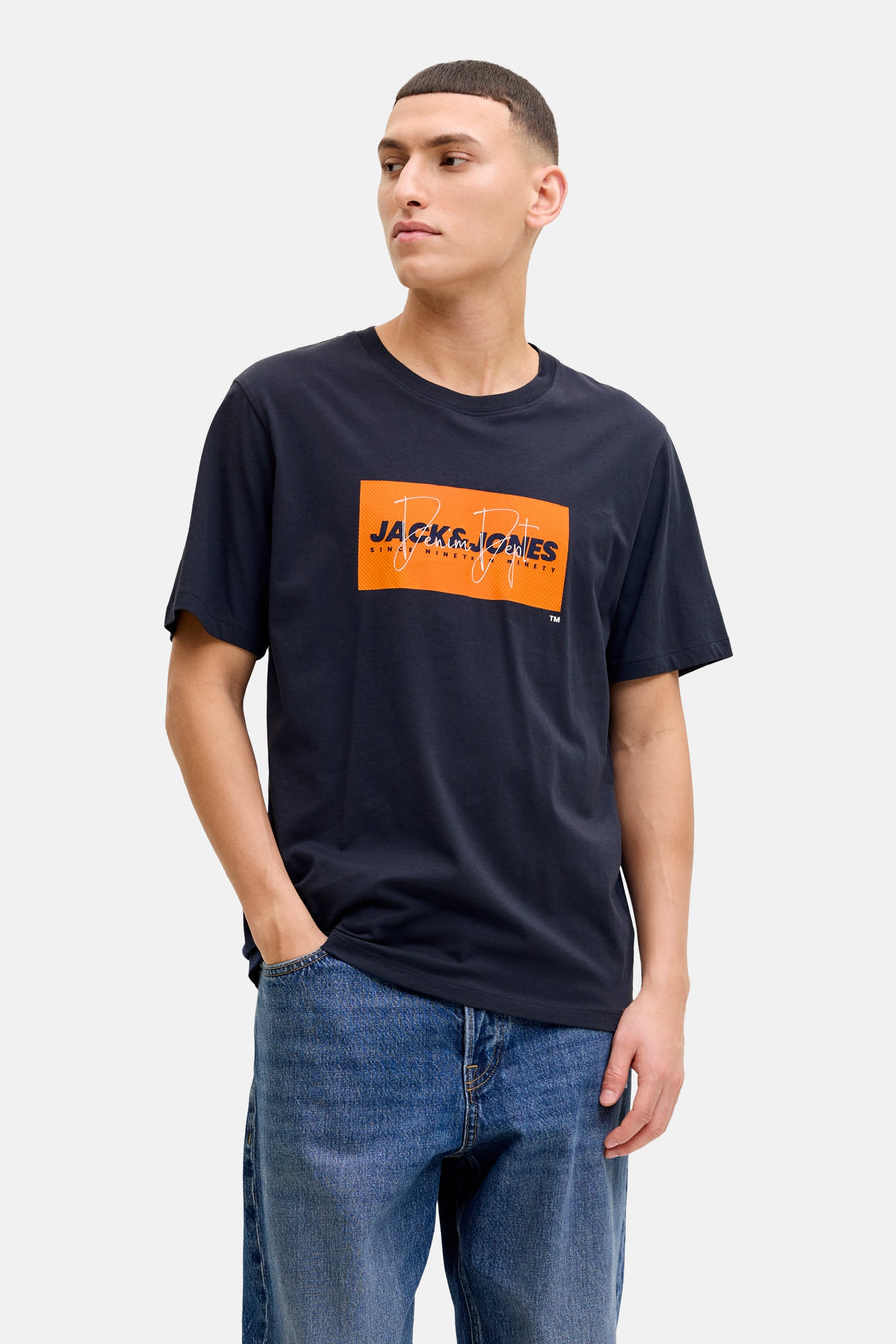 Blauw T-shirt met korte mouwen van JACK & JONES, met een oranje grafische print op de voorkant, gedragen met een wijde jeans.