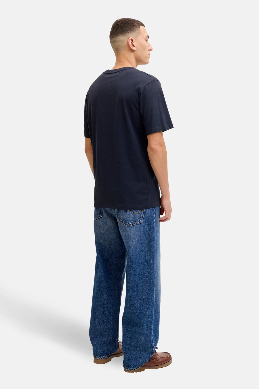 Blauw T-shirt met korte mouwen van JACK & JONES, gedragen met een wijde spijkerbroek en bruine bootschoenen.