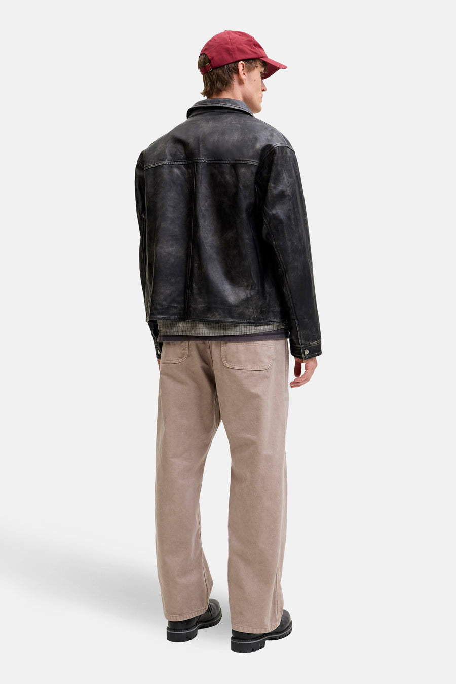 Beige broek van JACK & JONES JEANS INTELLIGENCE, gedragen met een leren jasje en een bordeauxrode pet.