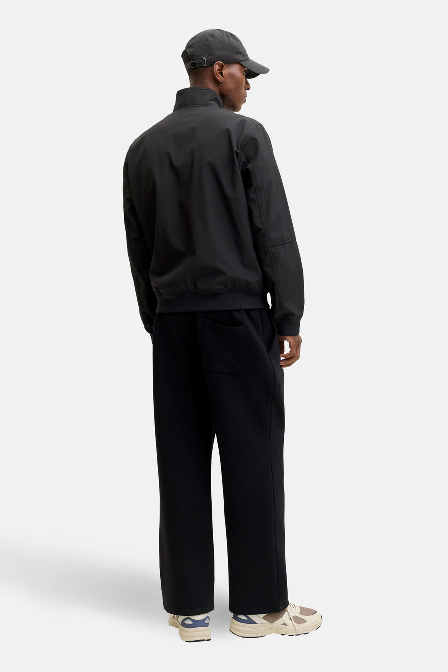 Zwarte regenjas van ORIGINALS BY JACK & JONES, gedragen met een zwarte broek en sportschoenen.