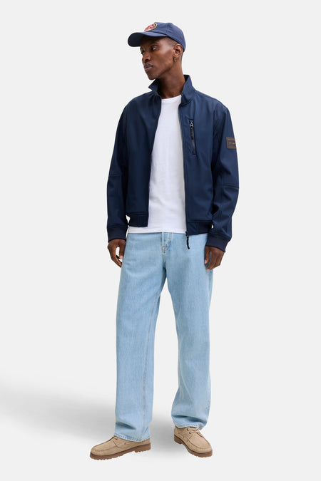 Veste de pluie bleue par ORIGINALS BY JACK & JONES avec fermeture éclair, portée sur un t-shirt blanc et un jean ample.