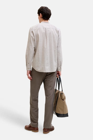Chemise à manches longues beige de JACK & JONES, col officier, plissée au dos, portée de dos avec un pantalon marron et un sac cabas.