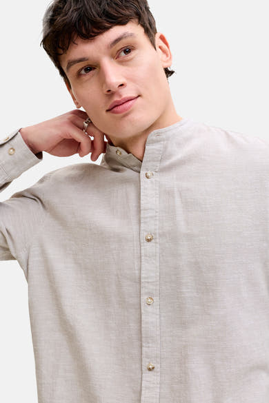 Chemise à manches longues beige de JACK & JONES avec col officier et texture lin, portée par un homme.