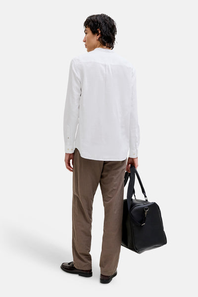 Chemise à manches longues blanche de JACK & JONES, avec une coupe décontractée, portée avec un pantalon marron.