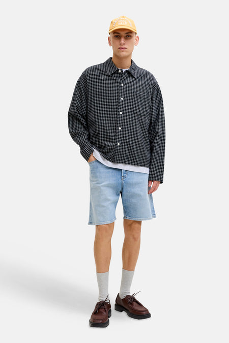 Short en denim bleu clair de JACK & JONES JEANS INTELLIGENCE, porté avec une chemise à carreaux, un t-shirt et des chaussures marron.