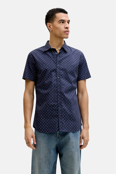Chemise bleue à manches courtes par PREMIUM by JACK & JONES, imprimée de motifs géométriques, portée avec un jean bleu.
