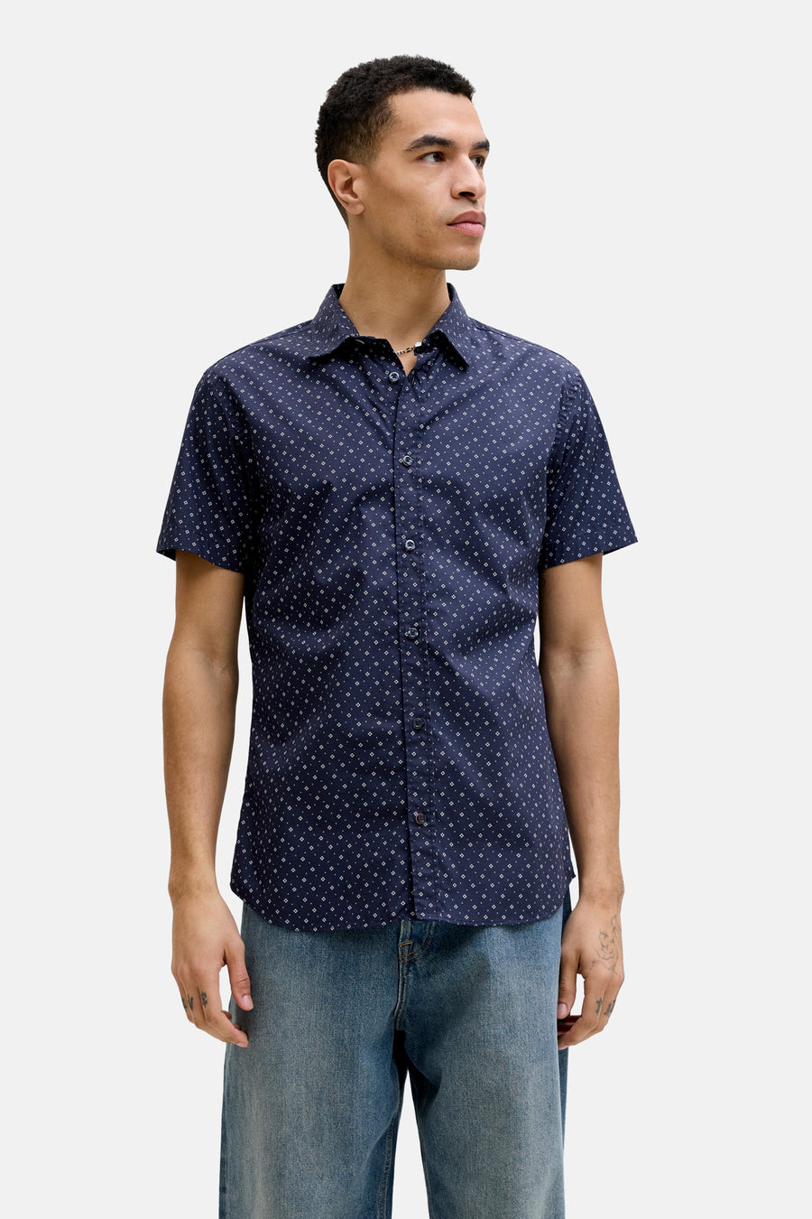 Chemise bleue à manches courtes par PREMIUM by JACK & JONES, imprimée de motifs géométriques, portée avec un jean bleu.
