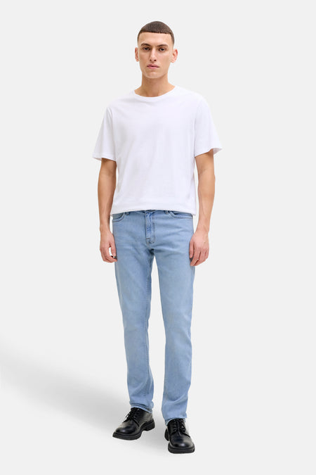 Jean slim en denim bleu clair de JACK & JONES JEANS INTELLIGENCE, porté avec un t-shirt blanc et des chaussures noires.
