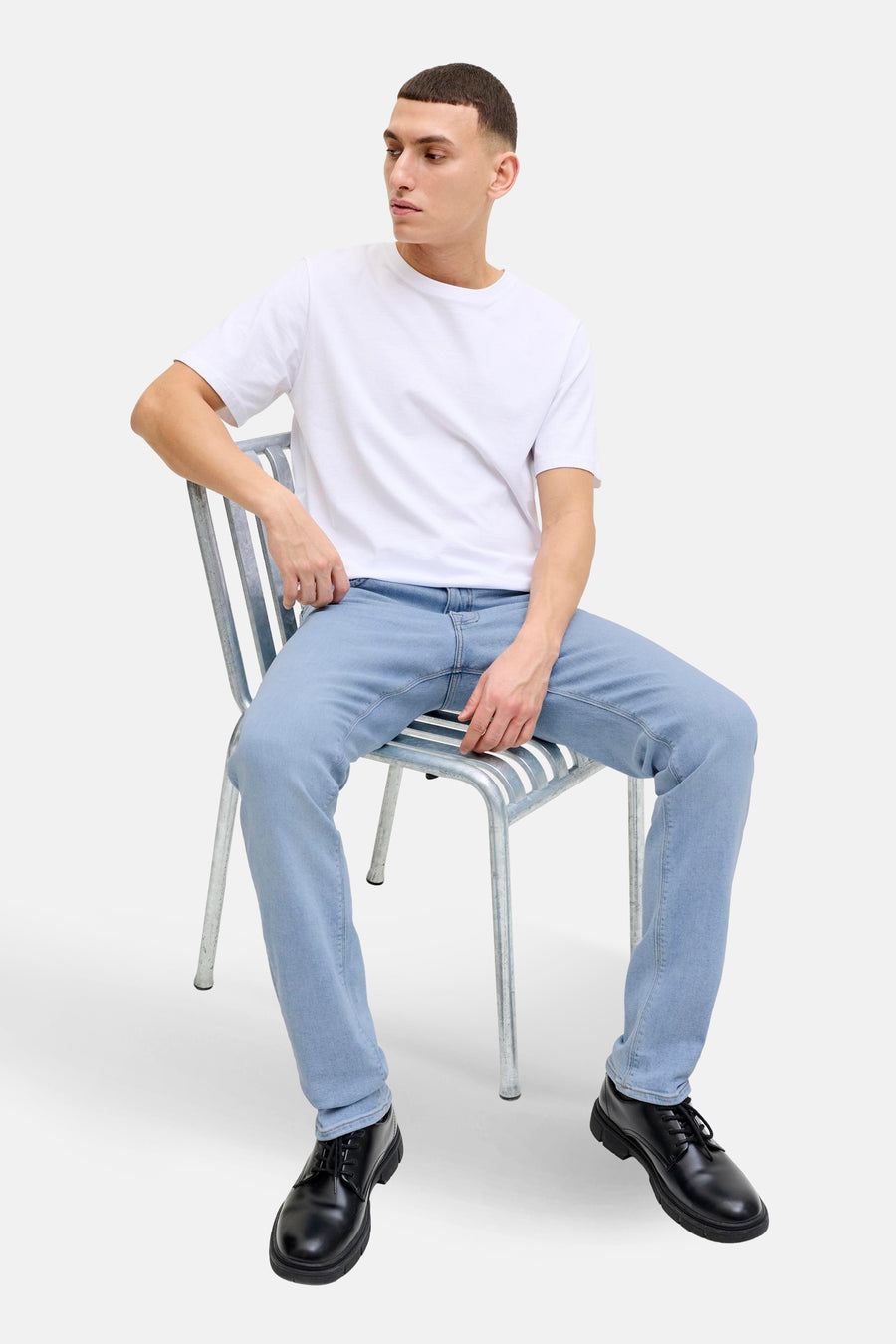 Jean slim en denim bleu clair de JACK & JONES, porté avec un t-shirt blanc uni et des chaussures noires à lacets.
