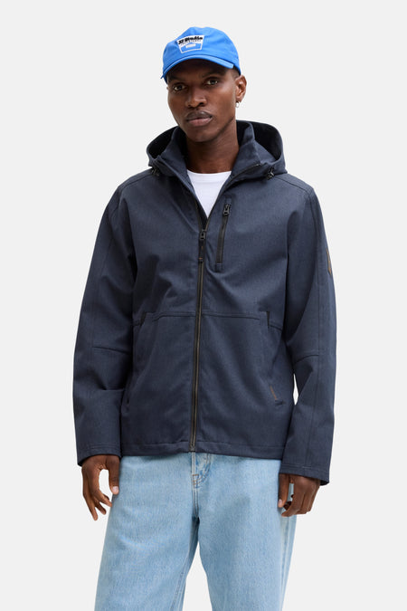 Korte marineblauwe jas van ORIGINALS BY JACK & JONES, met capuchon, gedragen over een wit T-shirt en een lichtblauwe jeans.