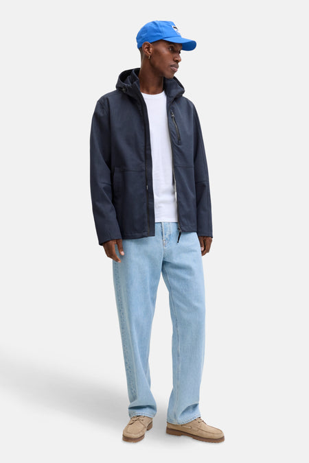 Veste courte bleu marine de ORIGINALS BY JACK & JONES, avec capuche, portée sur un t-shirt blanc et un jean bleu clair.