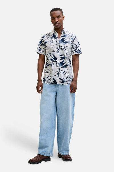 Chemise multicolore à manches courtes de JACK & JONES, à motif floral avec un pantalon ample et des chaussures marron.
