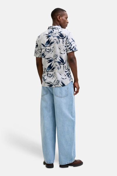 Chemise multicolore à manches courtes de JACK & JONES, imprimé avec des feuilles, portée avec un pantalon ample.
