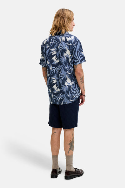 Blauw overhemd met korte mouwen en bladerpatroon van JACK & JONES, achterkant, gedragen met een marineblauwe korte broek.