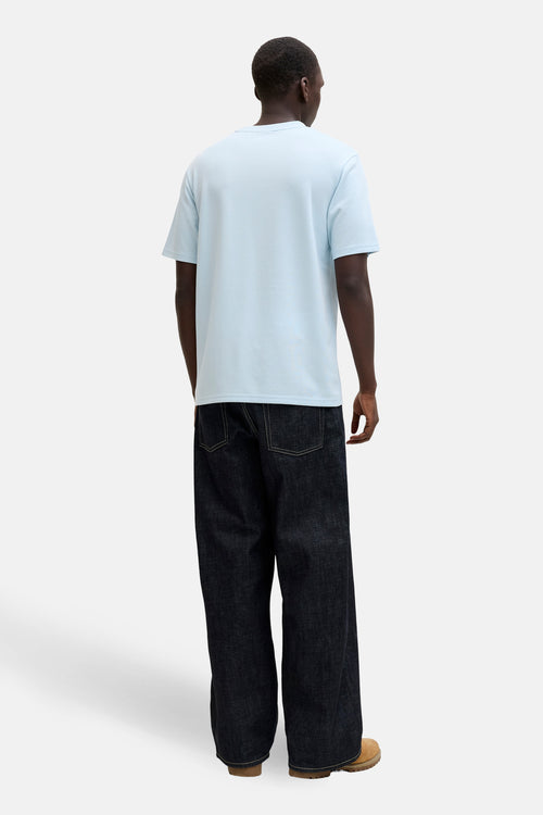 T-shirt à manches courtes bleu par PREMIUM by JACK & JONES, porté avec un jean large foncé et des chaussures marron.