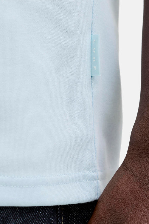 T-shirt à manches courtes bleu de PREMIUM by JACK & JONES, avec une étiquette décorative, et jean foncé visible.