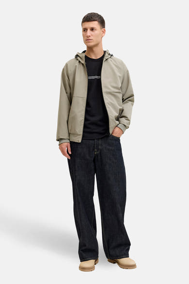 T-shirt noir à manches courtes de JACK & JONES, porté avec un blouson et un jean amples.