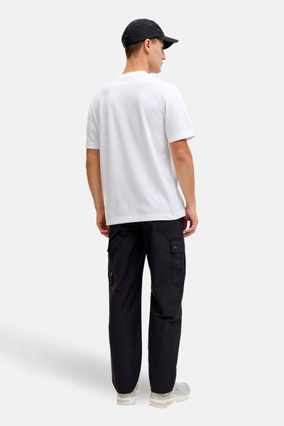 Wit T-shirt met korte mouwen van JACK & JONES, gedragen met een zwarte cargobroek en een pet.
