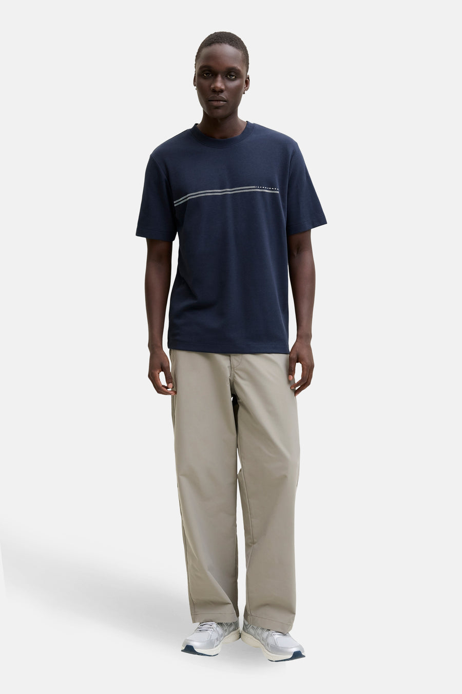 T-shirt à manches courtes bleu marine de JACK & JONES, avec deux rayures horizontales sur le devant et un pantalon beige.