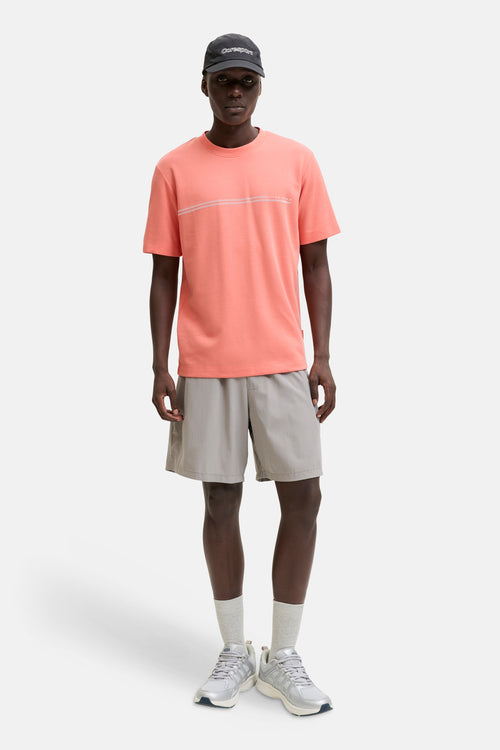 T-shirt orange de JACK & JONES avec lignes et inscription sur la poitrine, porté par un homme en short gris.