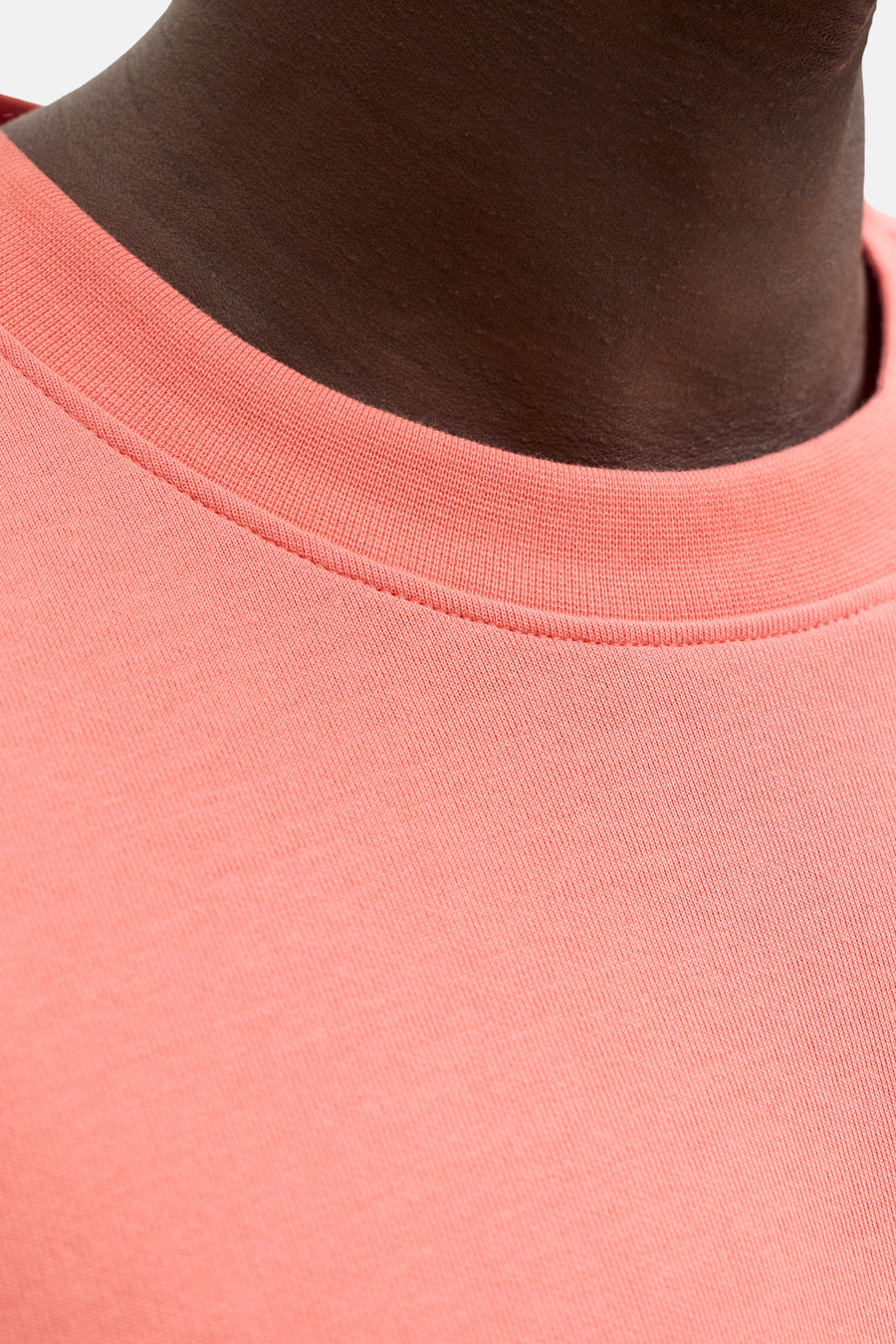 T-shirt orange de JACK & JONES, gros plan du col côtelé porté par une personne à la peau foncée.