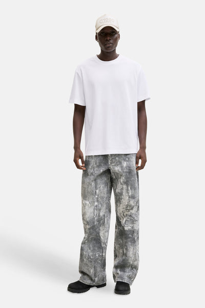 T-shirt blanc de JACK & JONES, porté avec un chapeau beige et un pantalon délavé gris et blanc.