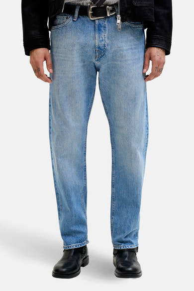 Jean fuselé en denim bleu clair de JACK & JONES JEANS INTELLIGENCE, porté avec des bottes en cuir noires.