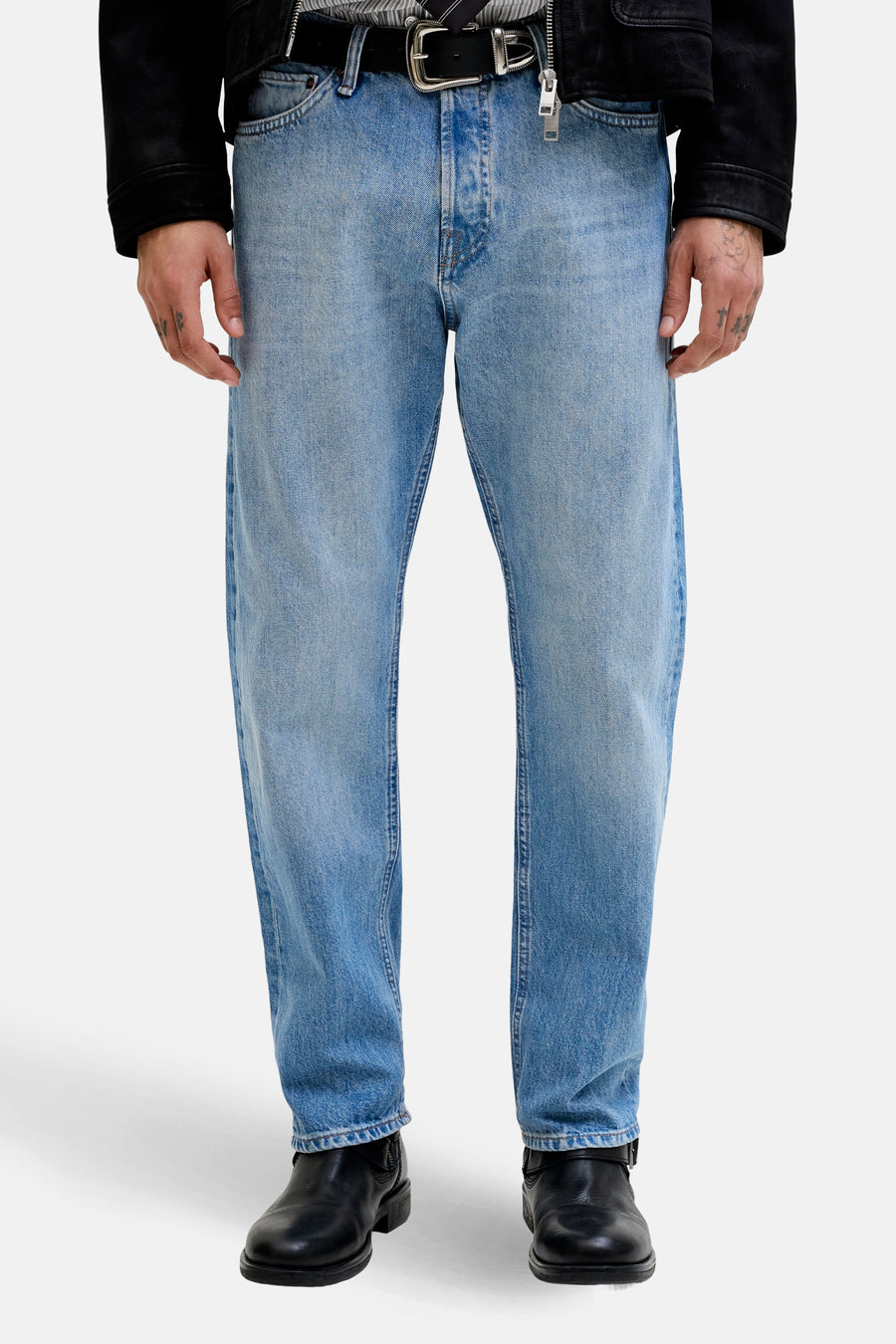 Jean fuselé en denim bleu clair de JACK & JONES JEANS INTELLIGENCE, porté avec des bottes en cuir noires.