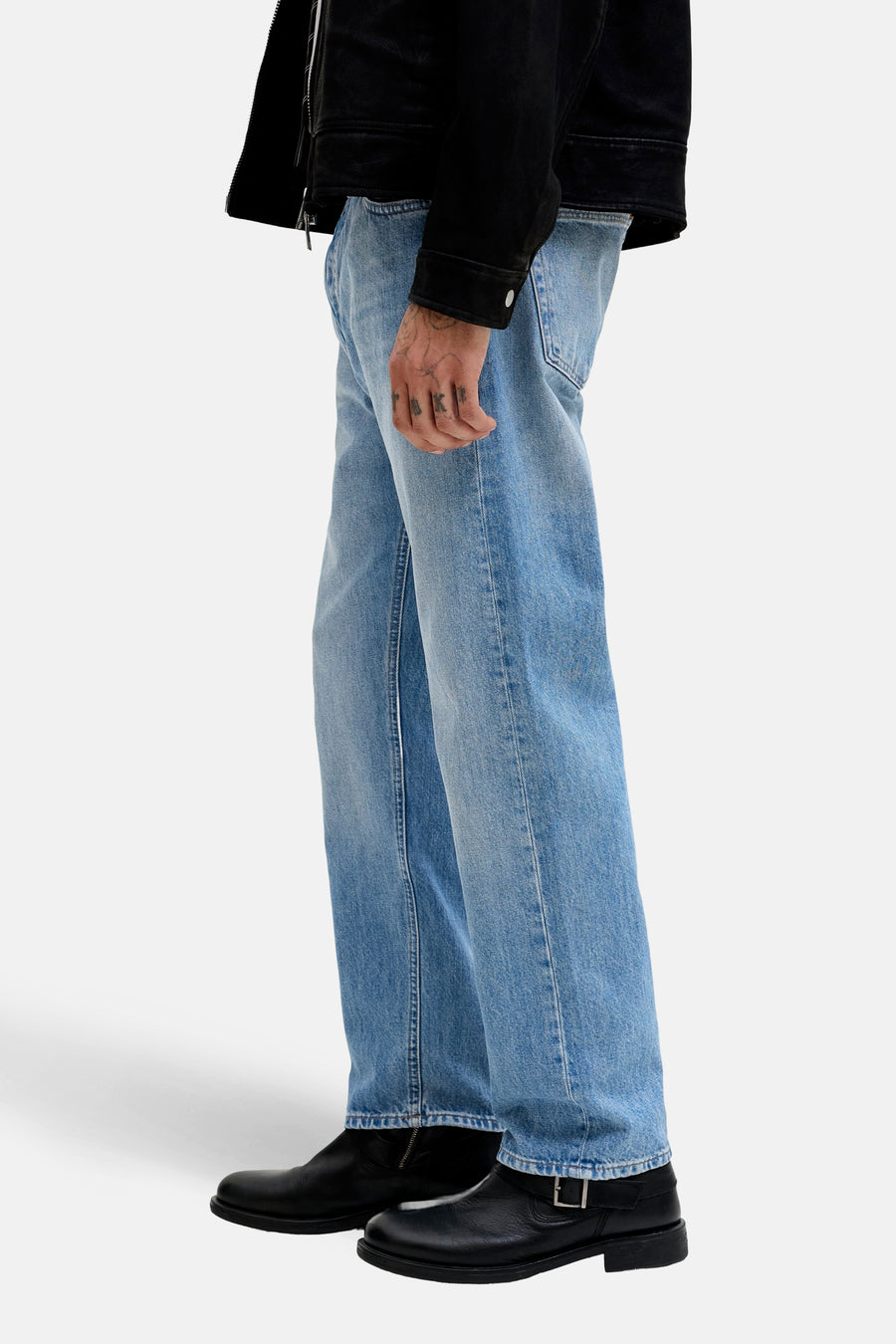 Jean tapered en denim bleu clair de JACK & JONES JEANS INTELLIGENCE, avec une coupe décontractée et des bottes en cuir noir.
