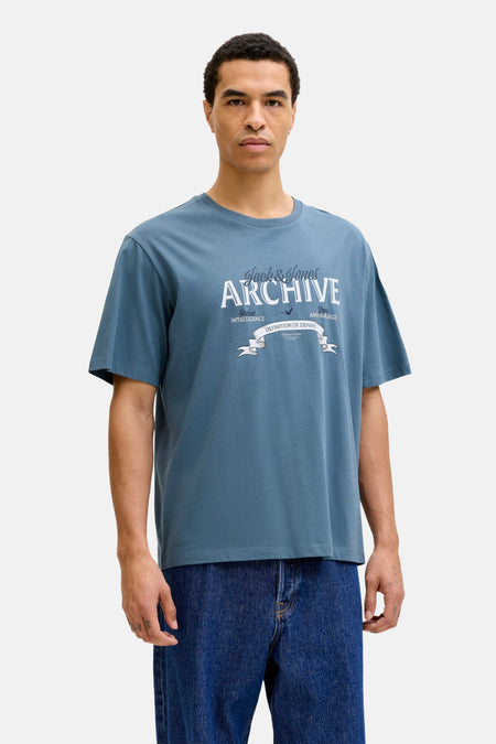 Blauw T-shirt met korte mouwen van ORIGINALS BY JACK & JONES, met witte tekstprint, gedragen met een wijde jeans en sneakers.
