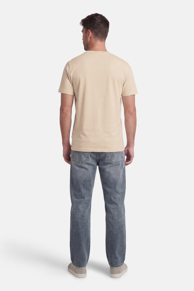 T-shirt à manches courtes beige par ORIGINALS BY JACK & JONES, porté avec un jean bleu et des chaussures décontractées, vue de dos.